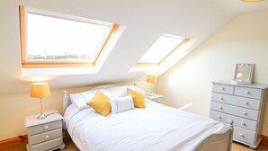 A bedroom with a bed, two nightstands, a dresser, and skylights. - The Blue Annex (Tralee)