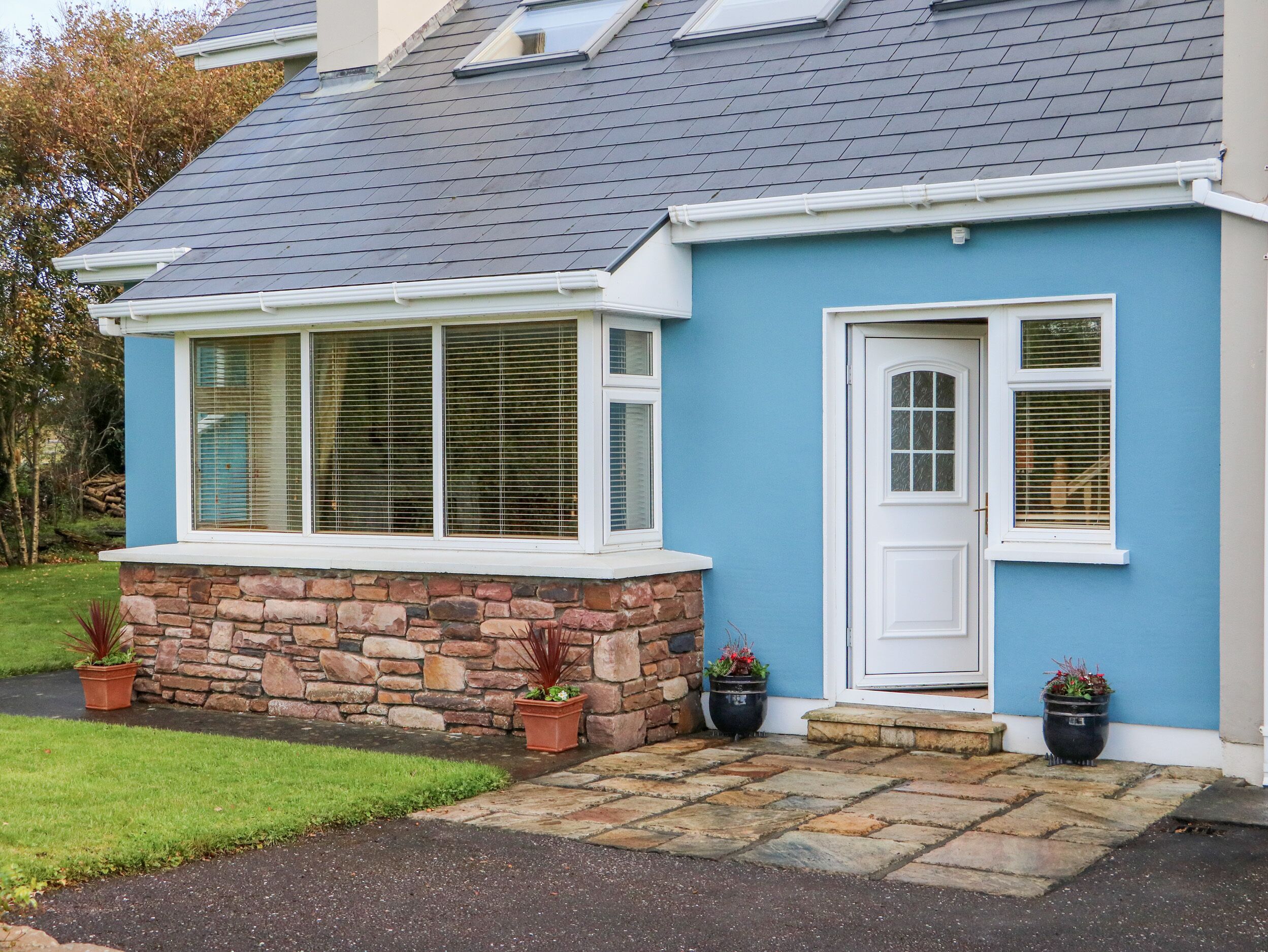 A house with a stone foundation, a blue exterior, and a grey roof.