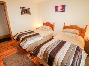 A room with two wooden beds, a wooden floor, a rug, and two wall-mounted lamps. - Reads Park (Galbally)