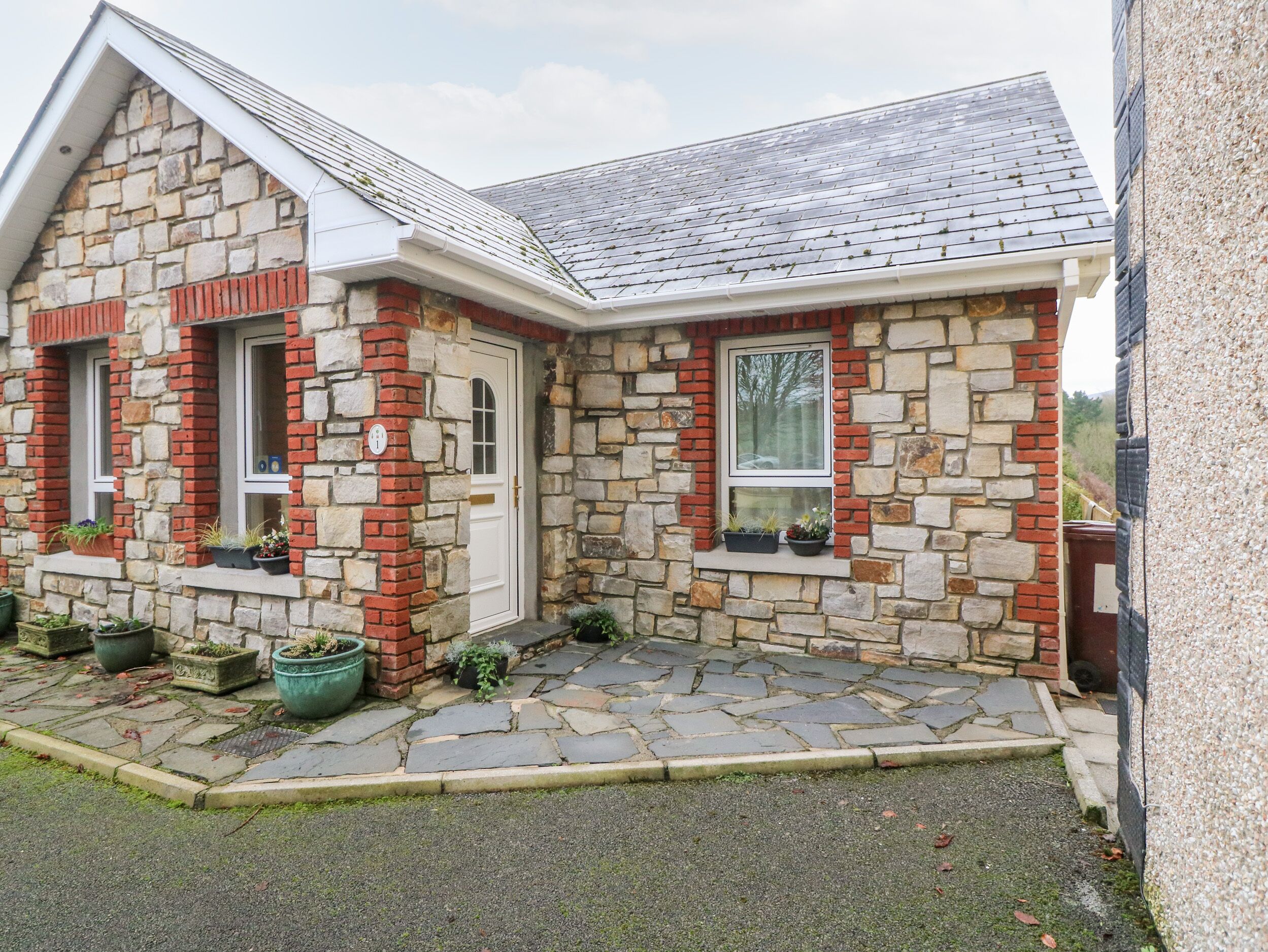 A stone house with a sloped roof, a front door, and windows with shutters.