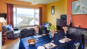 A dining area with a table set for four, a fireplace, and a view of the landscape through large windows.