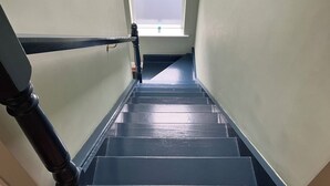A staircase with a handrail, a window at the top, and a small plant on the windowsill. - Silver Birch House (Carhoonahone)