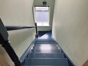 A staircase with a handrail, a window at the top, and a small plant on the windowsill. - Silver Birch House (Dunloe Upper)