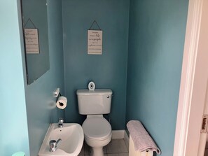 A bathroom with a toilet, sink, and a towel rack.