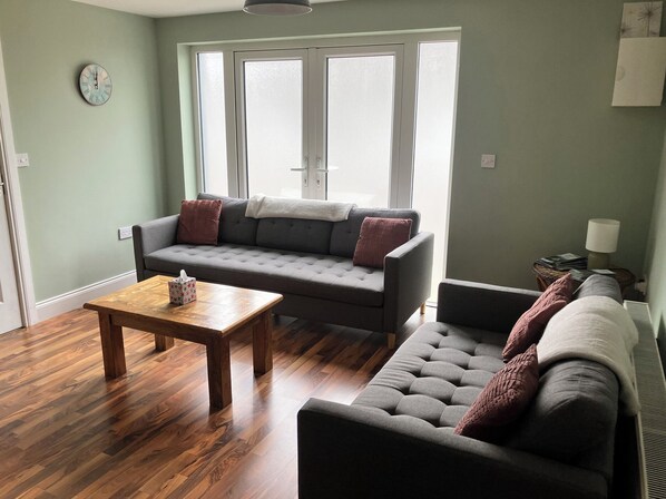 A living room with a sofa, a coffee table, and a window with blinds.
