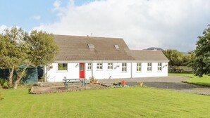 A white house with a red door, a gravel driveway, and a grassy yard. - Ben View (Renvyle)