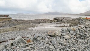 A rocky beach with a stone wall and a red fence. - Ben View (Renvyle)