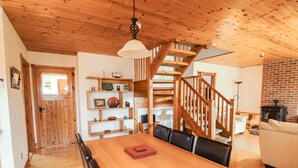 A wooden interior with a dining table, chairs, a staircase, and a fireplace. - Silver Birch (Creegh)
