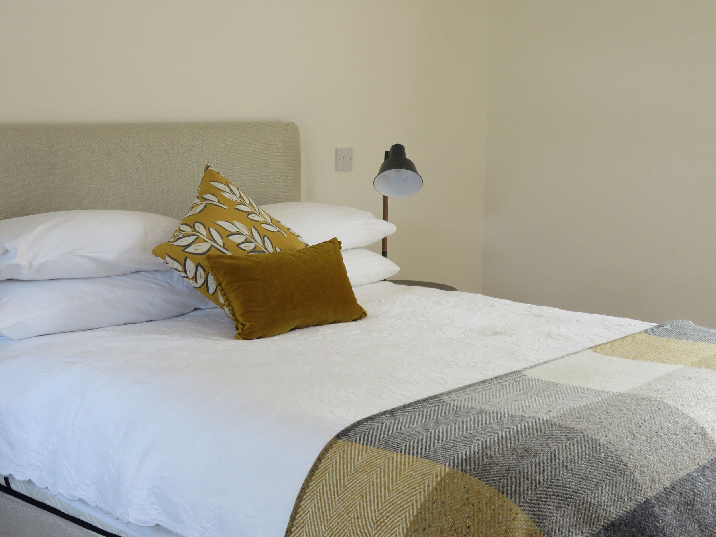 A neatly made bed with white linens and a patterned throw.
