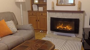 A living room with a fireplace, a sofa, a coffee table, and a lamp.