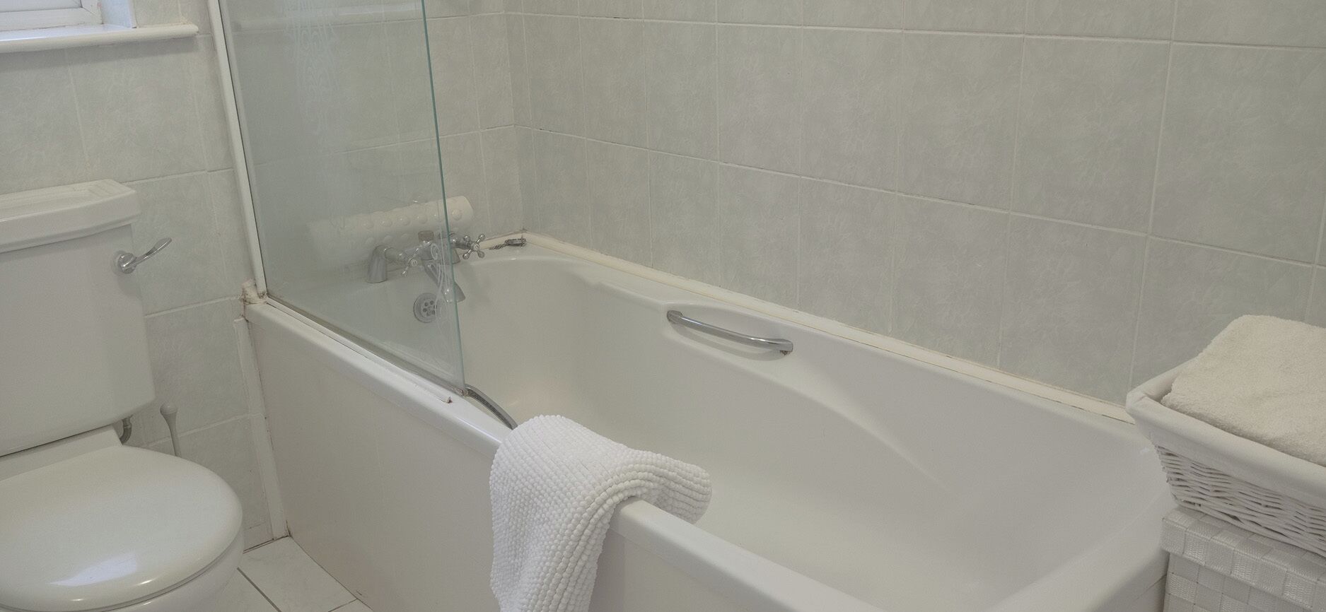Un baño con inodoro, ducha con cerramiento de vidrio y bañera.