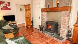 Una sala de estar acogedora con chimenea de ladrillo, sofá de cuero y televisor sobre un mueble de madera.