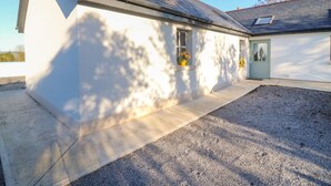 Ein eingeschossiges Haus mit geneigtem Dach, Schornstein und einer kleinen Veranda.