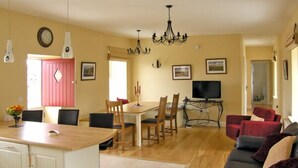 Un amplio espacio de sala con una mesa de comedor, un sofá y una cocina con una isla central.