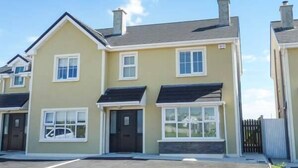 A row of two-story houses with a flat roof, a front porch, and a garage. - 63 Moinin (Kilkee)