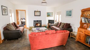 Ein gemütliches Wohnzimmer mit Kamin, zwei Sofas, einem Couchtisch und einem Bücherregal.