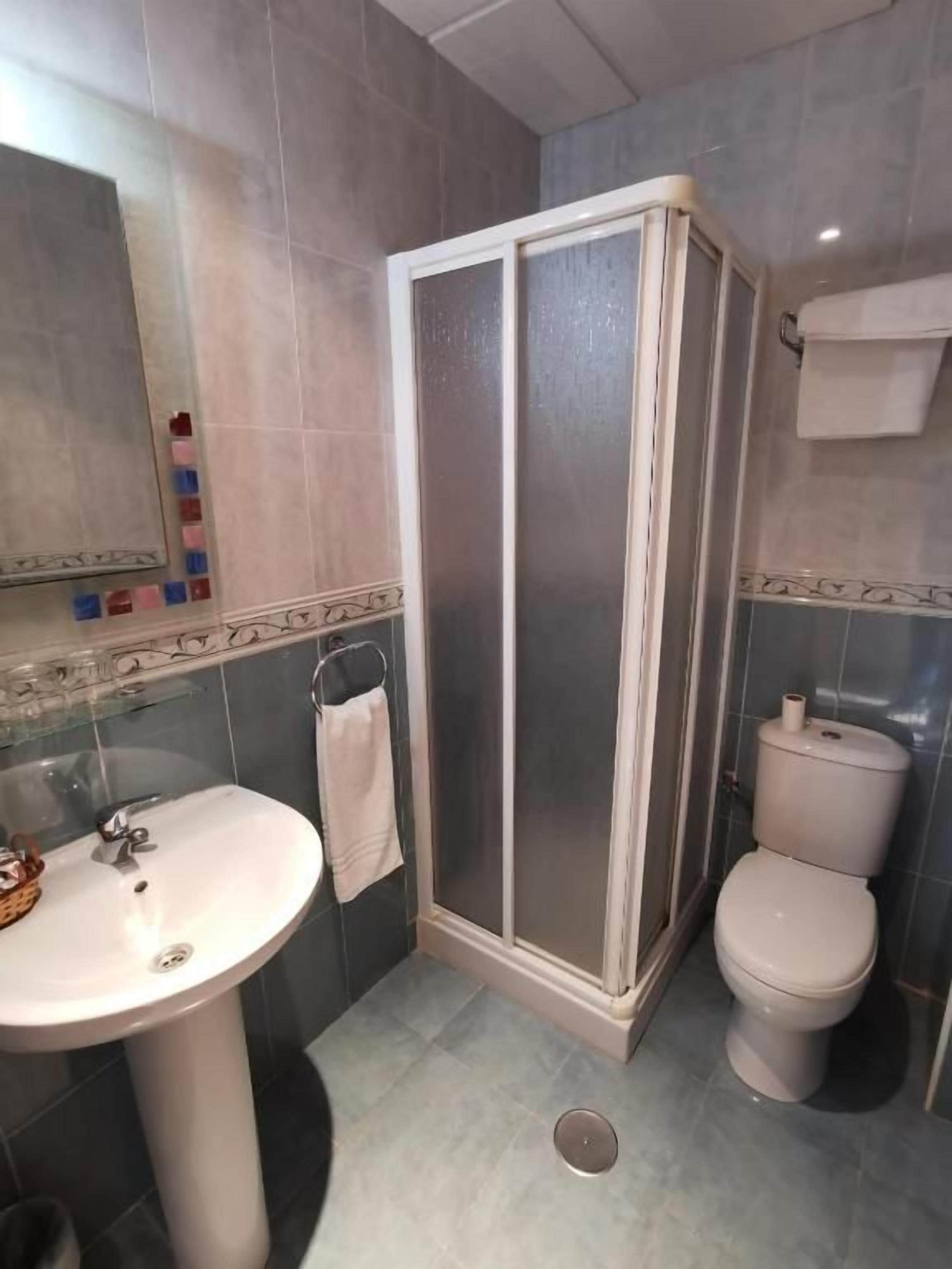 Un baño con cabina de ducha, inodoro, lavabo y espejo.