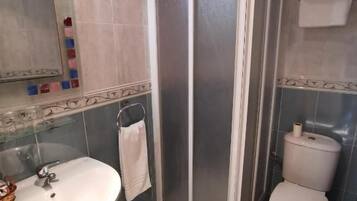 Un baño con cabina de ducha, inodoro, lavabo y espejo.
