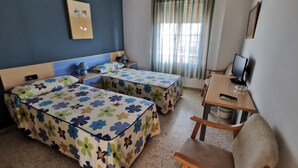 A hotel room with two beds, a desk with a computer, a chair, and a window with curtains. - Hostal Talavera (Talavera la Real)