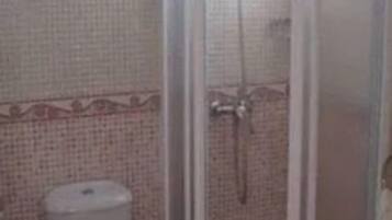 Un baño con inodoro, cabina de ducha y pared de azulejos.
