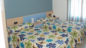 A room with two beds, each with floral-patterned bedding, a small bedside table, and a headboard. - Hostal Talavera (Talavera la Real)
