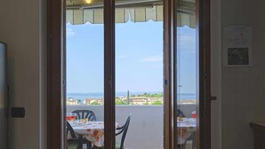 A balcony with a table and chairs, overlooking a coastal view.