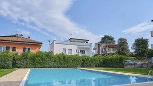 A residential area with a swimming pool, houses with balconies, and a clear sky.