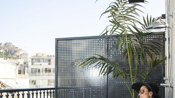 A bathtub with a towel, a suitcase, and a table with grapes on a balcony. - Pame Paradiso (Athens)