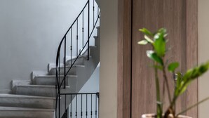 A staircase with a metal railing leading to a wooden door. - Pame Paradiso (Athens)