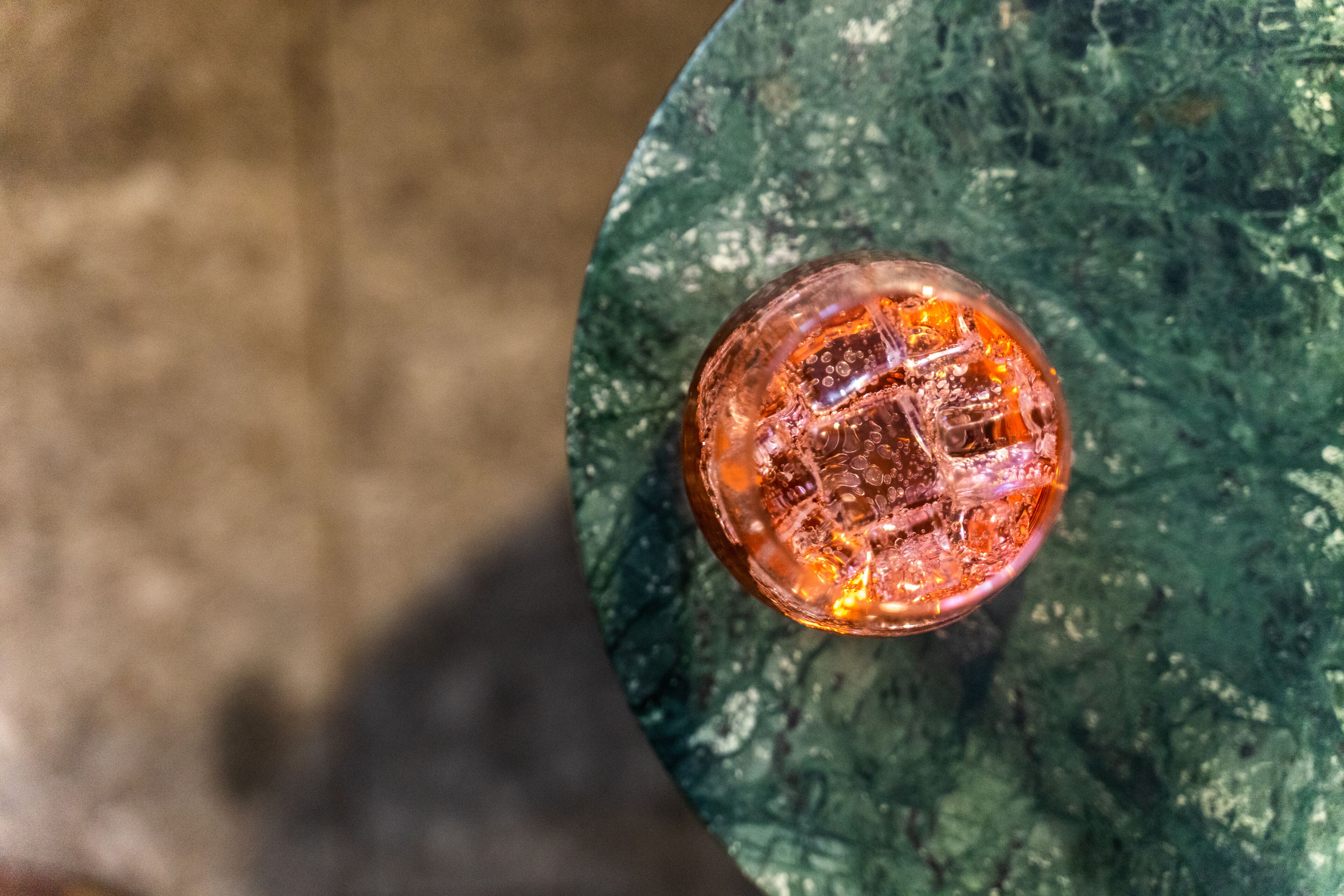 A top-down view of a round table with a glass object on it, possibly a drink, and a green marble-like surface.