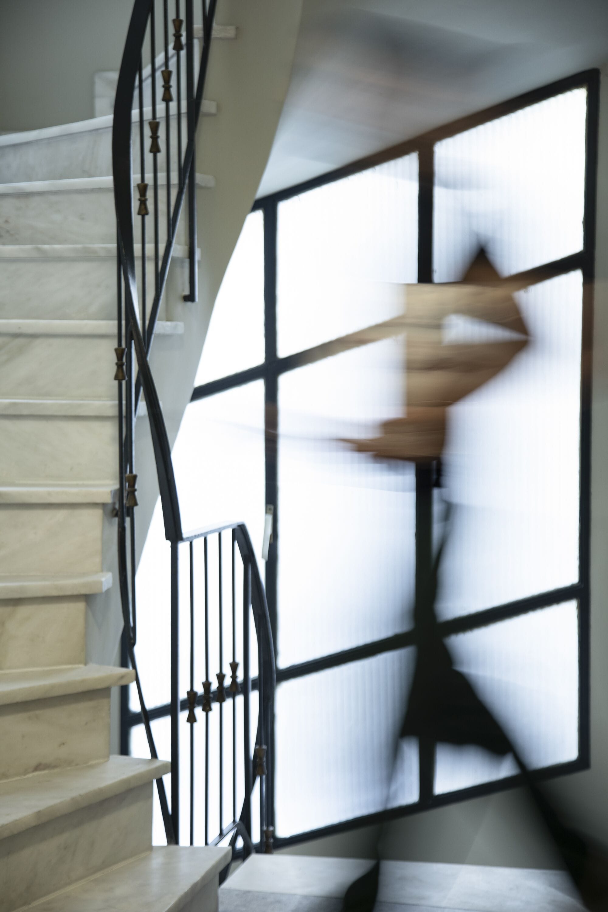 A staircase with a black railing and a large window with a grid pattern.