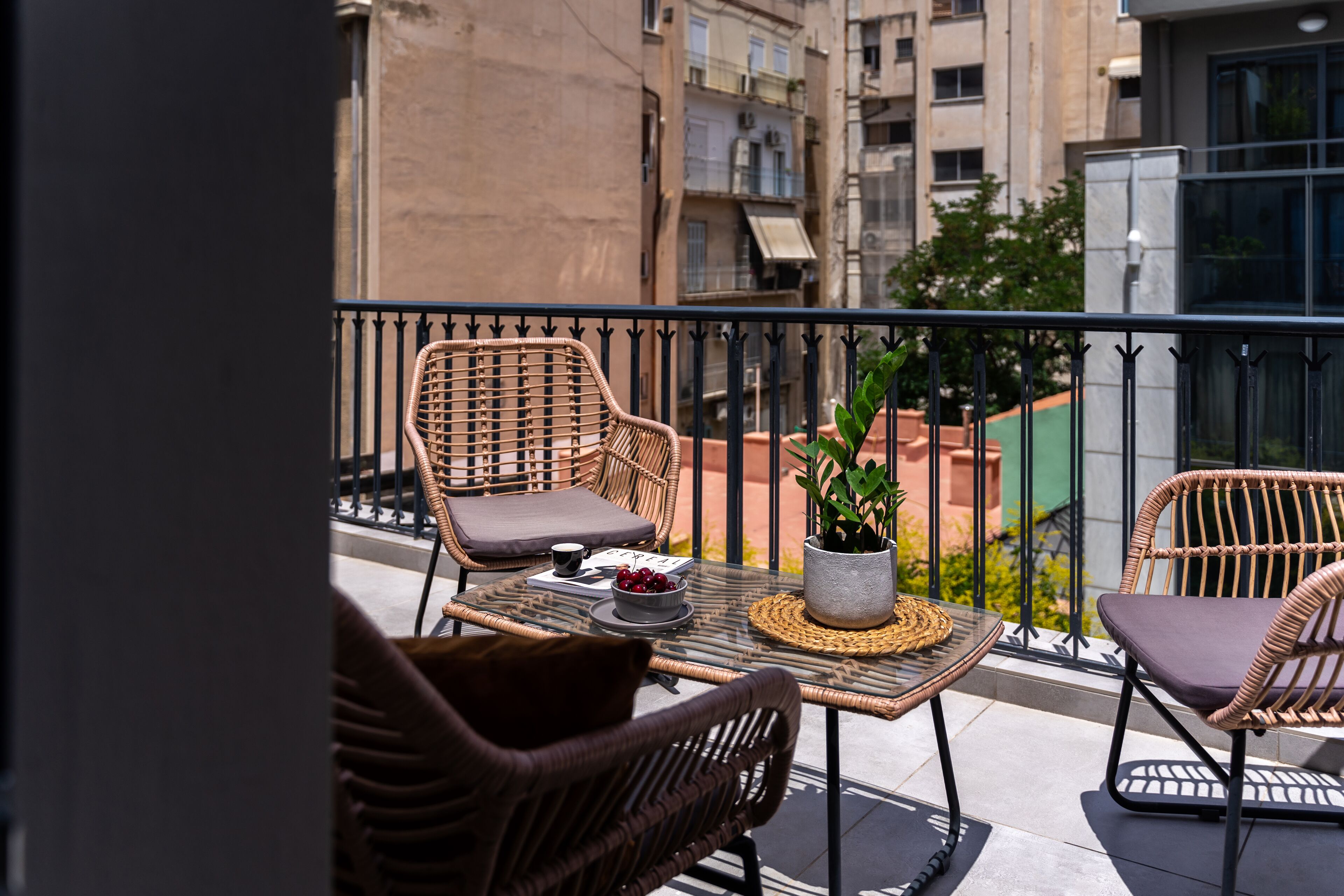 A balcony with wicker furniture, a table with a bowl of fruit, and a potted plant.