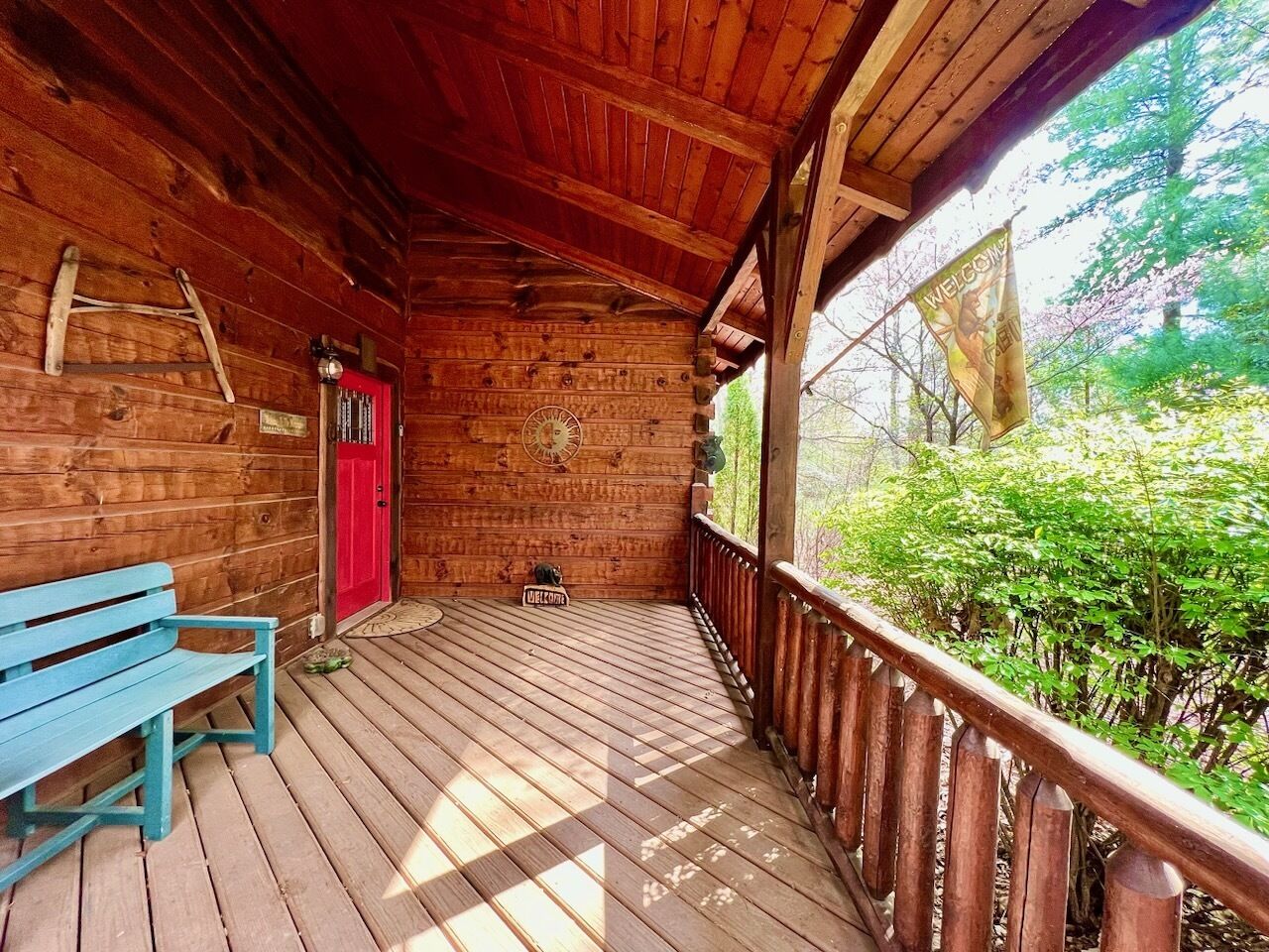 A wooden cabin with a porch, a red door, and a blue bench.