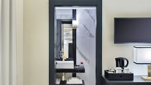Uma casa de banho moderna com uma toucador preta, um espelho e uma máquina de café preta sobre o balcão.