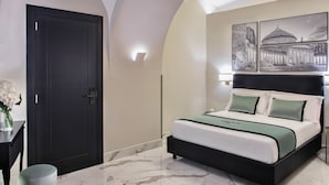 Quarto moderno com piso de mármore, porta escura, cama com roupa de cama verde e branca e luminária fixada na parede.
