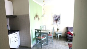Cocina compacta con zona de comedor, suelo de baldosas, una pequeña mesa con sillas y un aplique de pared.