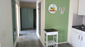 Una cocina con paredes verdes, un armario blanco, una encimera negra y un carro pequeño blanco.