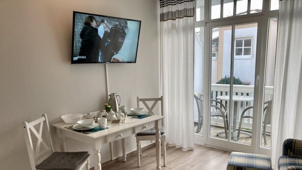 En matplats med ett bord för två, en tv som är monterad på väggen och utsikt över balkongen.