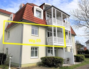 Un bâtiment à deux étages doté d’un balcon, d’un petit jardin et surplombant un ciel dégagé.