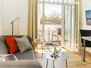 Een moderne woonkamer met een bank, een klein rond tafeltje en uitzicht door een glazen deur op een terras.
