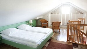 A room with two beds, a chair, a table, and a wooden railing. - Apartment Rosenhof 07 - Wh. 07 (Kühlungsborn)