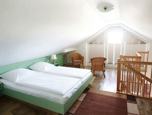 Una stanza con due letti, una sedia, un tavolo e una ringhiera in legno.