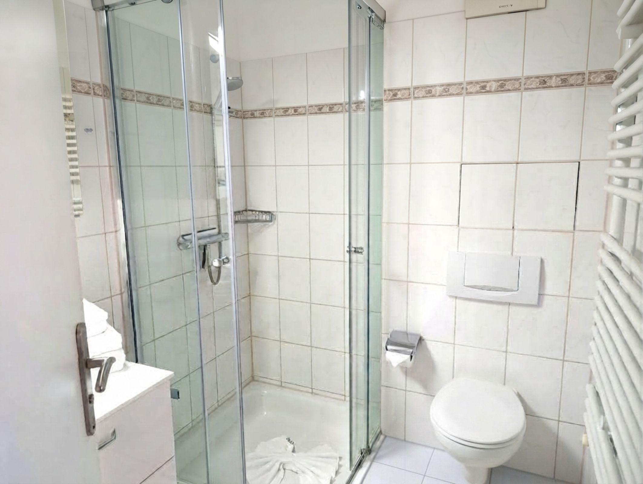 Un baño con ducha envuelta en vidrio, inodoro y lavamanos.