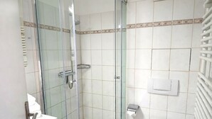 A bathroom with a glass-enclosed shower, a toilet, and a sink. - Apartment Rosenhof 07 - Wh. 07 (Kühlungsborn)
