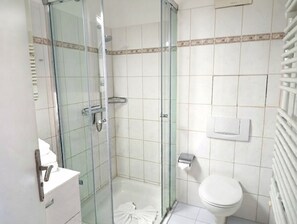 Un bagno con doccia vetrata, un water e un lavandino.