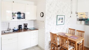 A modern kitchen with white cabinets, a built-in oven, and a coffee maker. - Apartment Rosenhof 07 - Wh. 07 (Kühlungsborn)