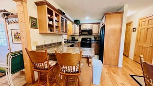 Una cocina con armarios de madera, encimera de granito y un comedor con dos sillas.