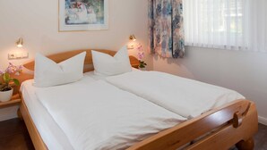 A neatly made double bed with white linens, a wooden headboard, and two bedside lamps. - Apartment Rosenhof 14 - Wh. 14 (Kühlungsborn)