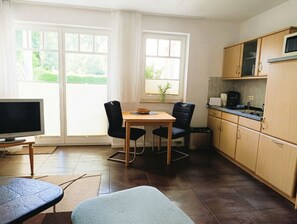 A compact living space with a dining area, kitchenette, and a television. - Apartment Rosenhof 14 - Wh. 14 (Kühlungsborn)