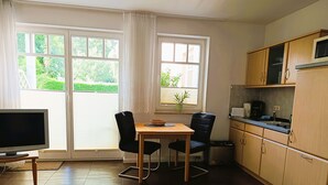A compact living space with a dining area, kitchenette, and a TV. - Apartment Rosenhof 14 - Wh. 14 (Kühlungsborn)